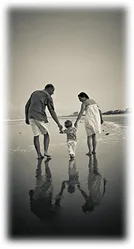 A father, mother and young child walking together on the beach